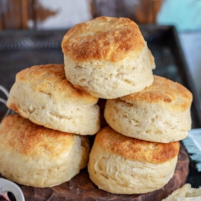 golden brown biscuits stacked high on wood board.