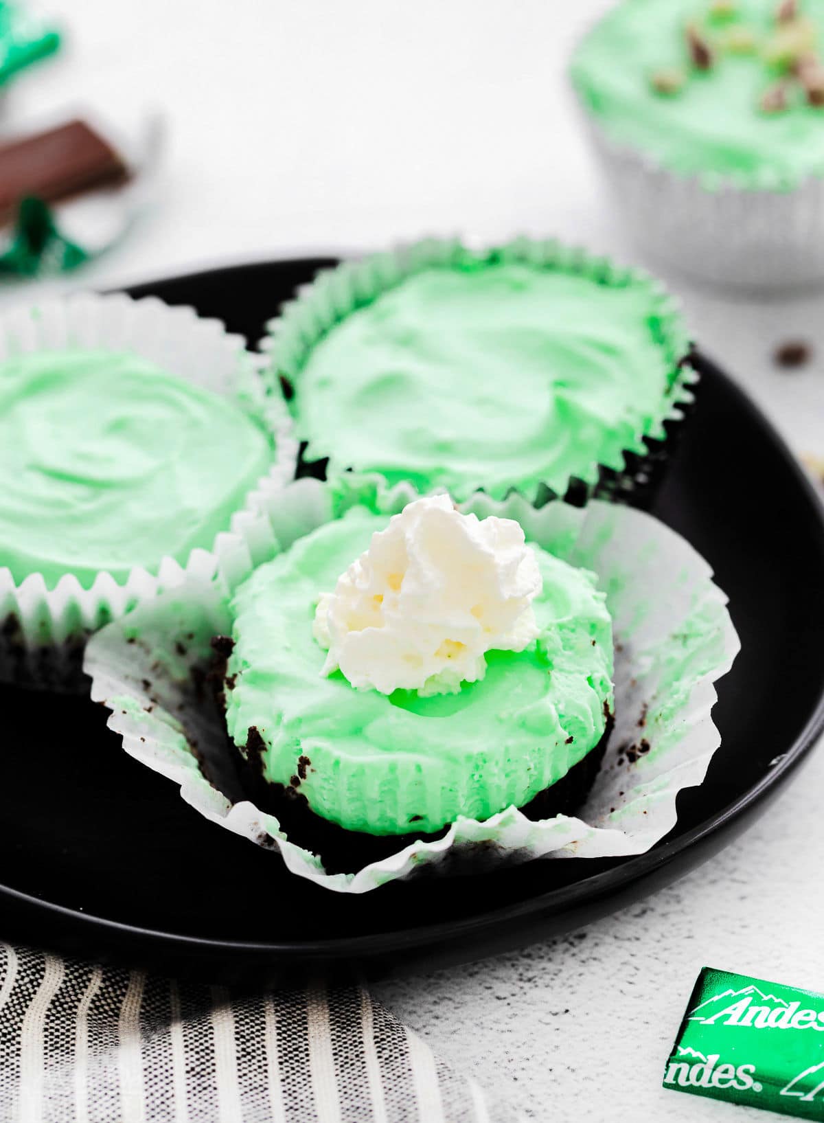 three grasshopper mini cheesecakes on black plate.