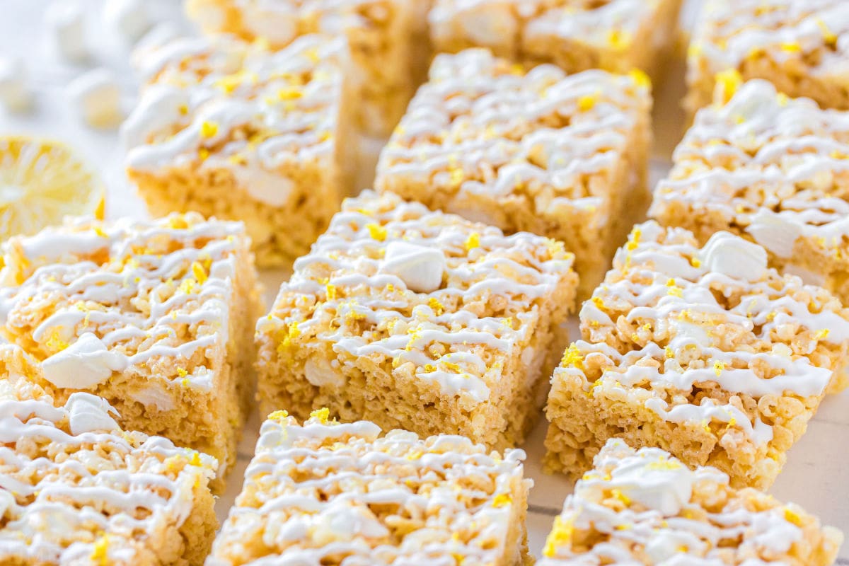 rice krispie treats cut into squares on white surface with white drizzle on top of treats.