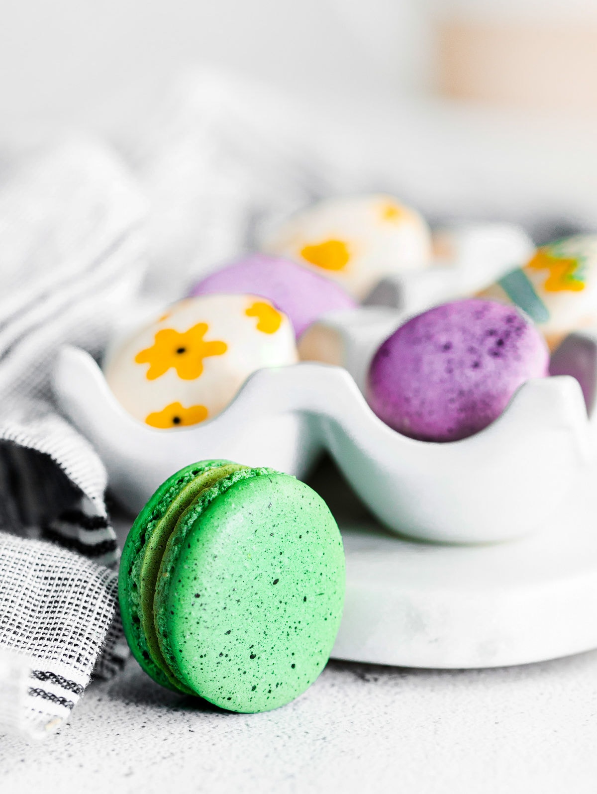 green speckled macaron sitting in front of egg tray.