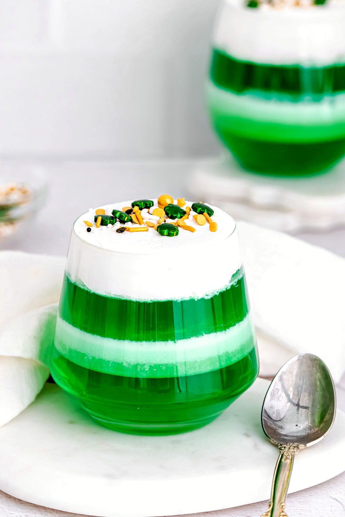 layered green and white jello cups on marble surface.