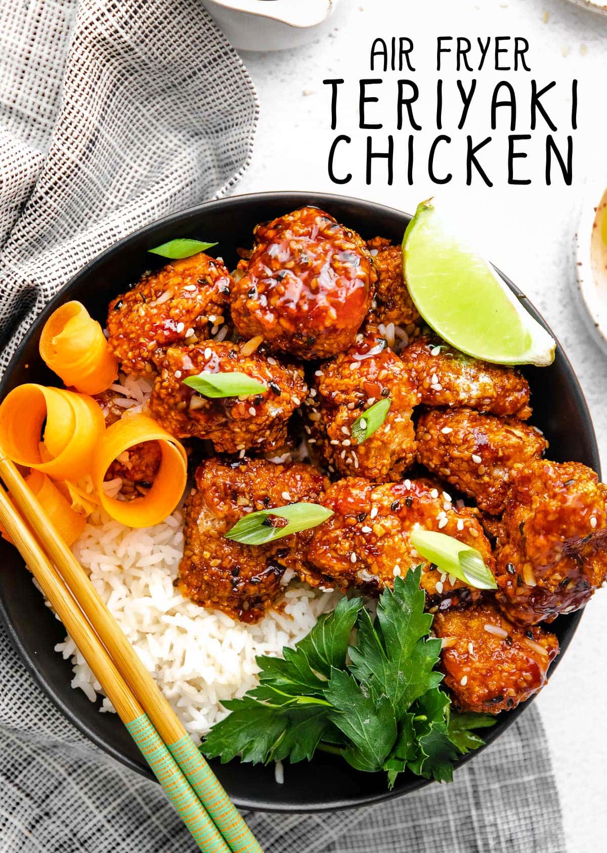 teriyaki chicken with rice in a black bowl next to a striped black and white towel. title overlay at top of image.