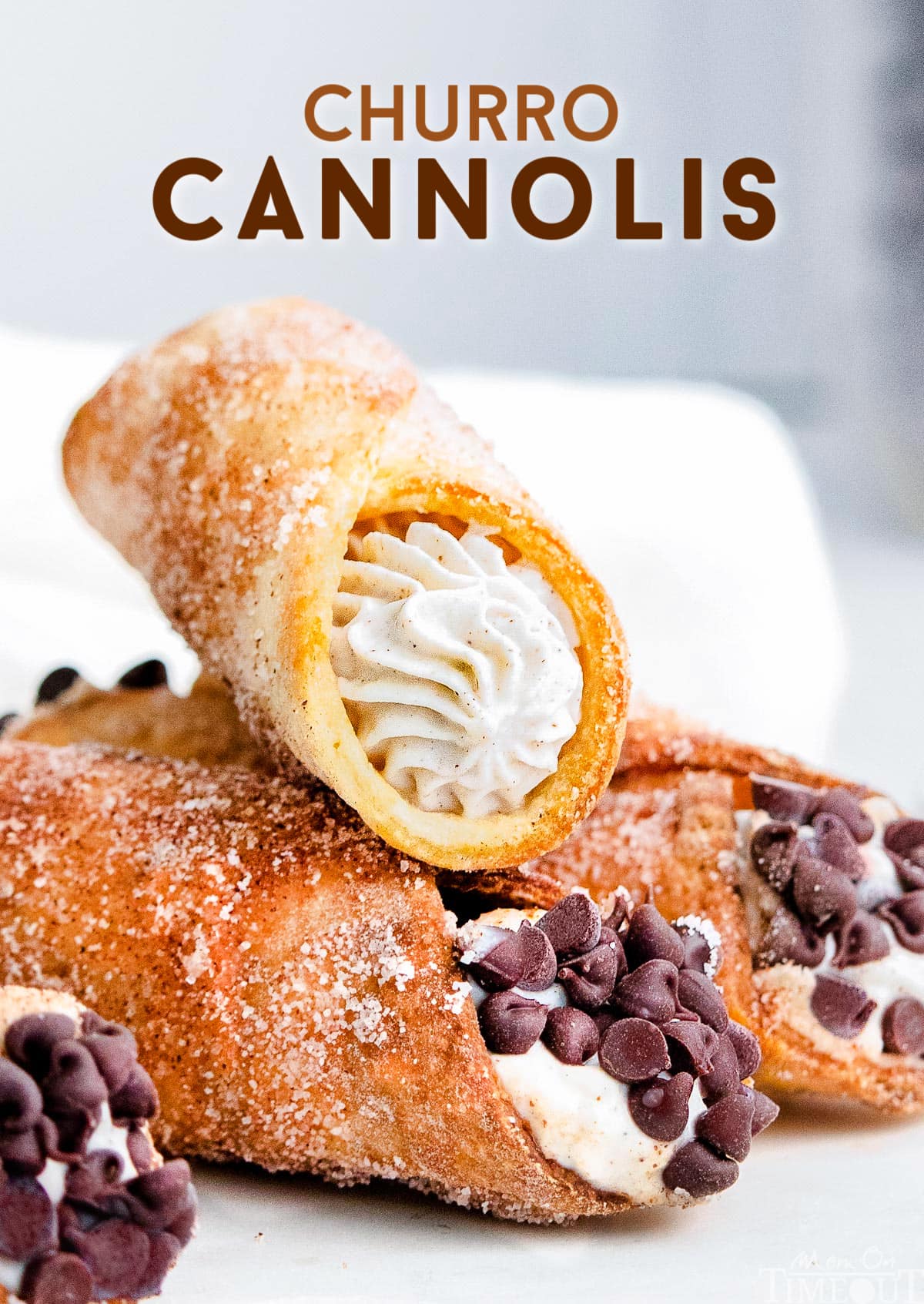 three cannolis sitting on white plate with cannoli filling and chocolate chips. 