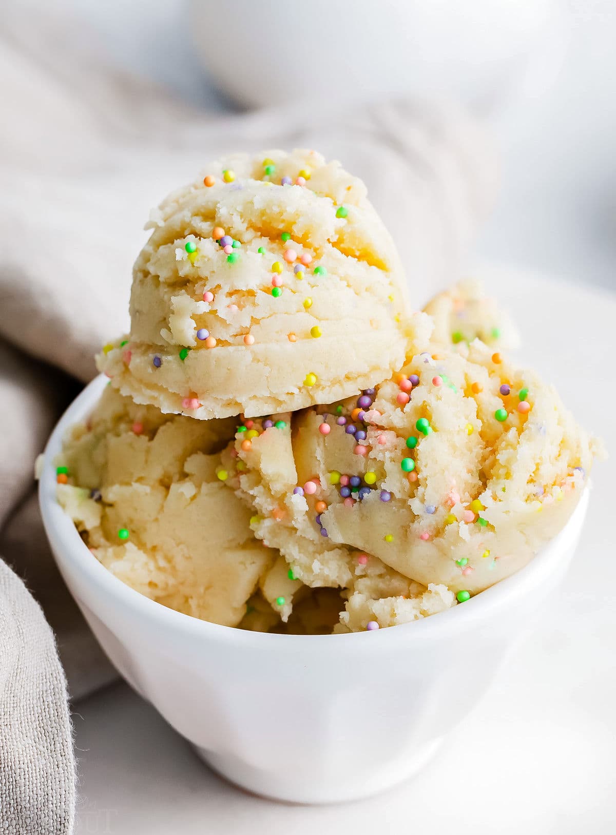 edible cookie dough with sprinkles in white bowl.