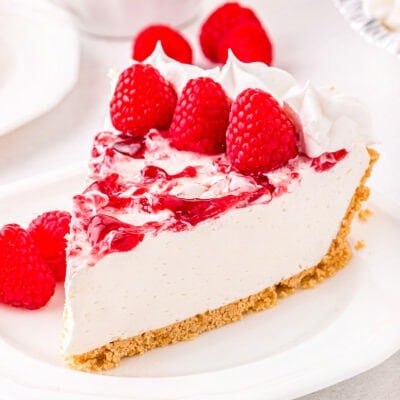 piece of cheesecake on plate garnished with fresh raspberries.