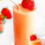 strawberry mango smoothie in clear glass with fresh strawberries scattered about. image has color blocks on top and bottom with strawberry mango smoothie text overlay.