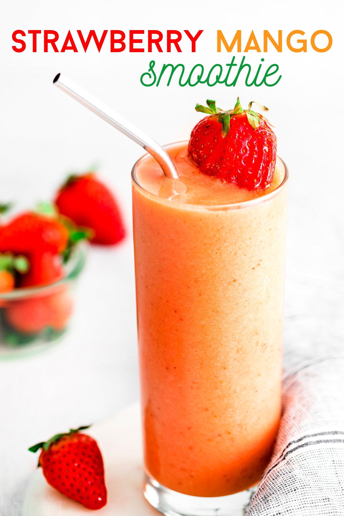 strawberry mango smoothie in tall glass with steel straw and garnished with fresh strawberries. title overlay at top of image.