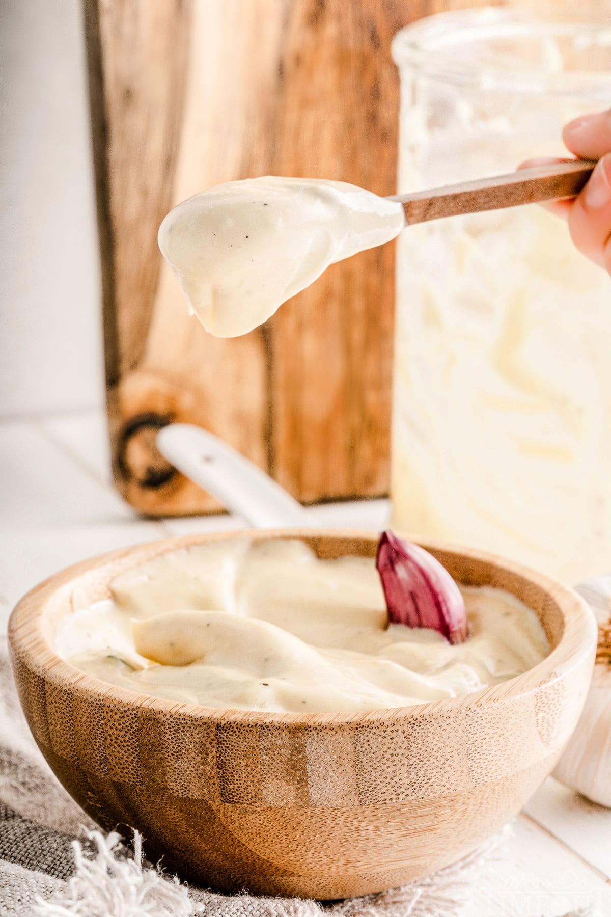 spoonful of aioli held above a bowl of aioli.