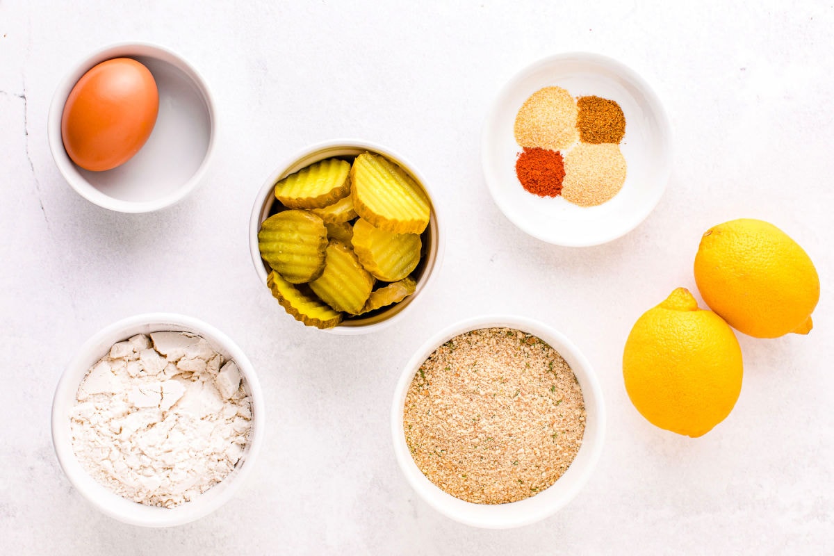 air fryer pickles ingredients measured out in small bowls on white surface.