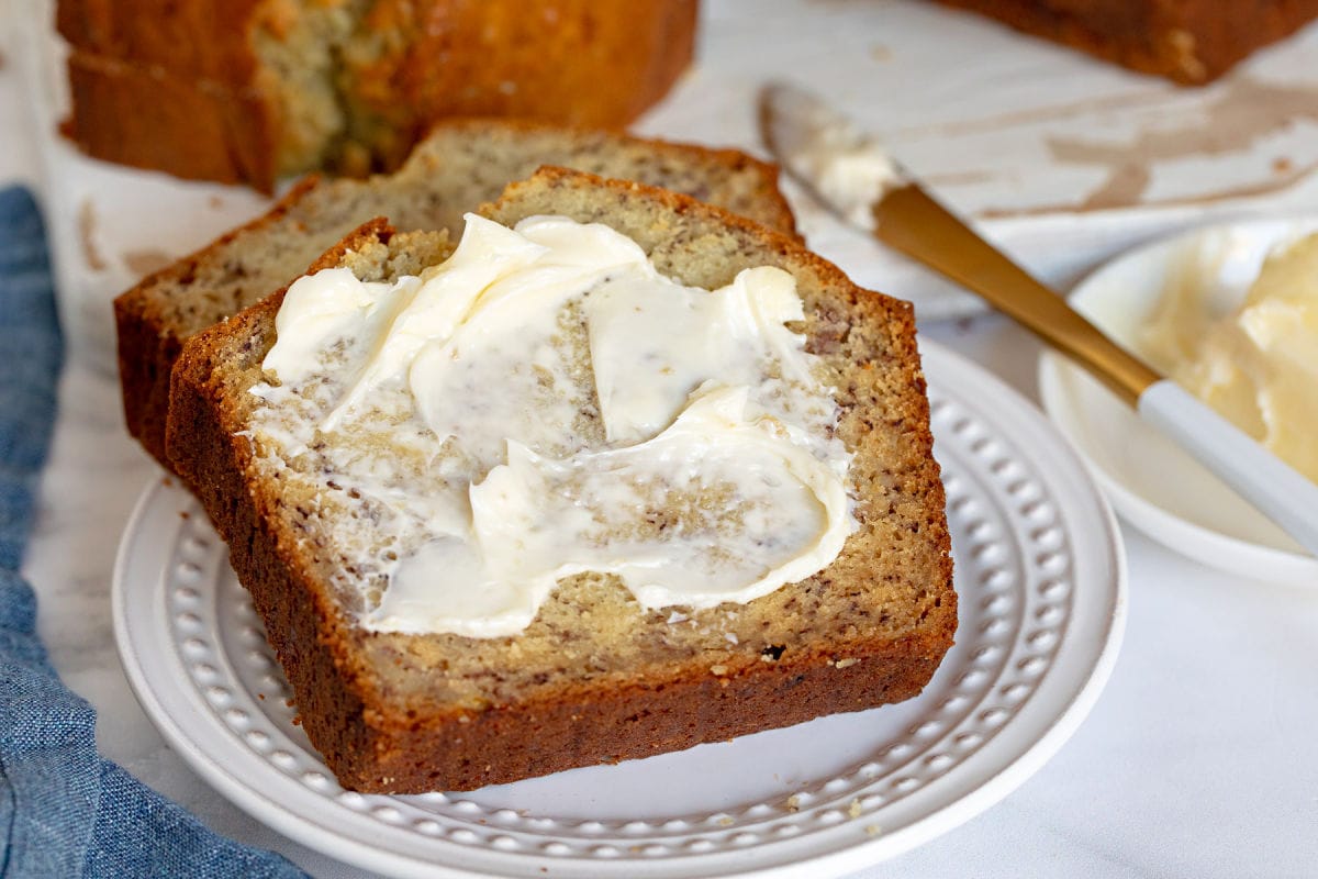 bread with butter sitting on a white plate.