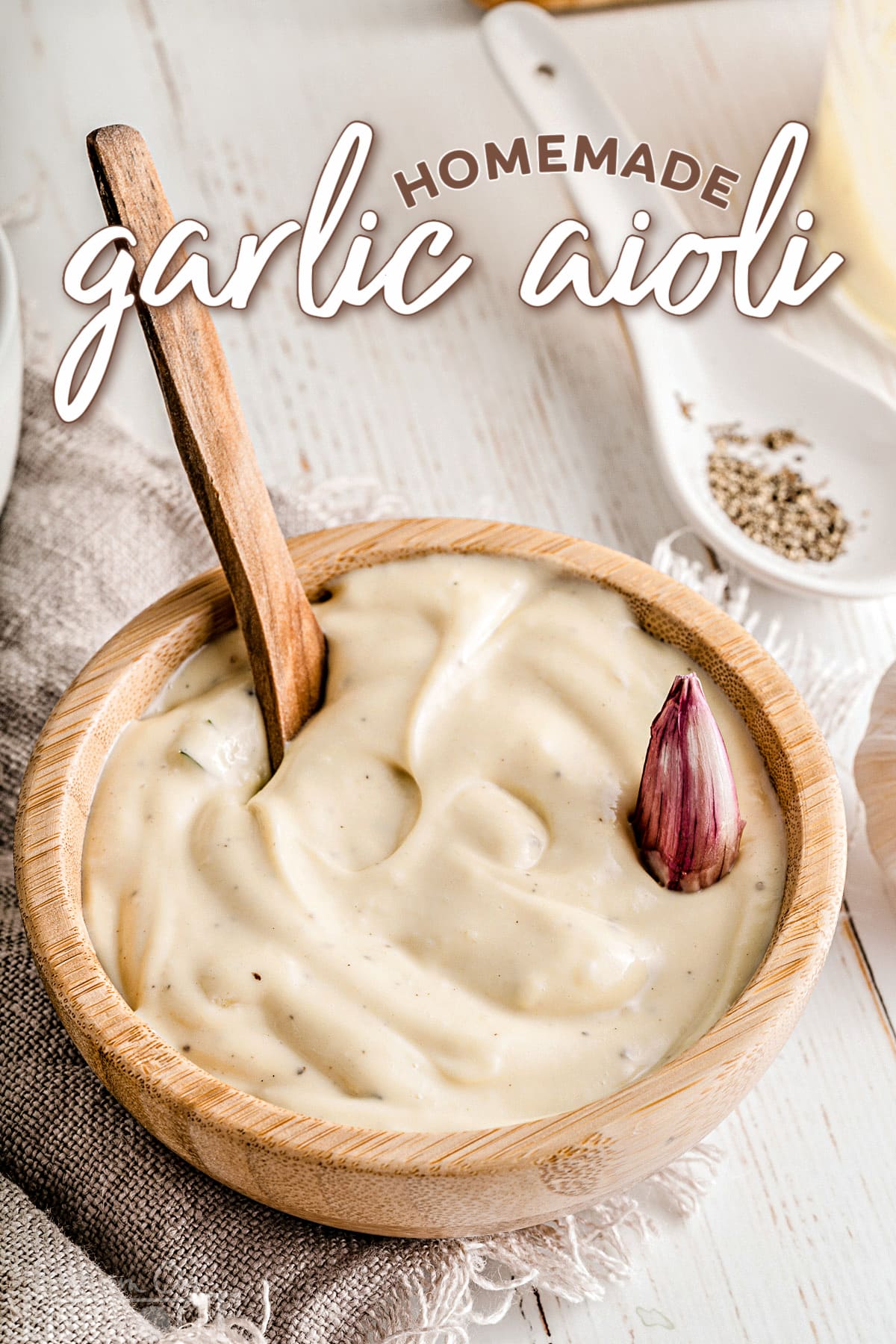garlic aioli in small wood bowl topped with garlic clove and title overlay at top of image.