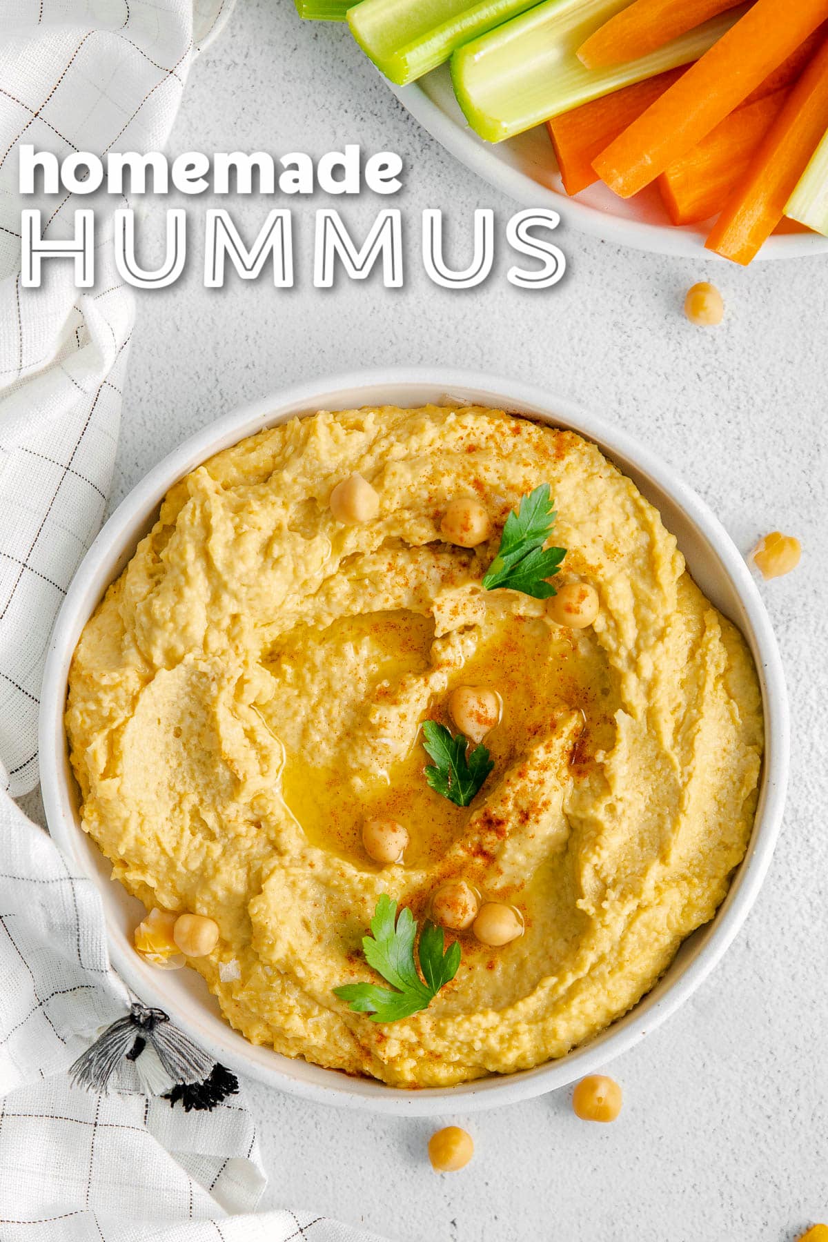 hummus in shallow white bowl with carrots and celery on a plate next to it. title overlay at top of image.