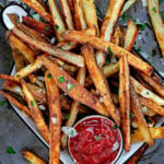 pile of oven fries on baking sheet with small bowl of ketchup.