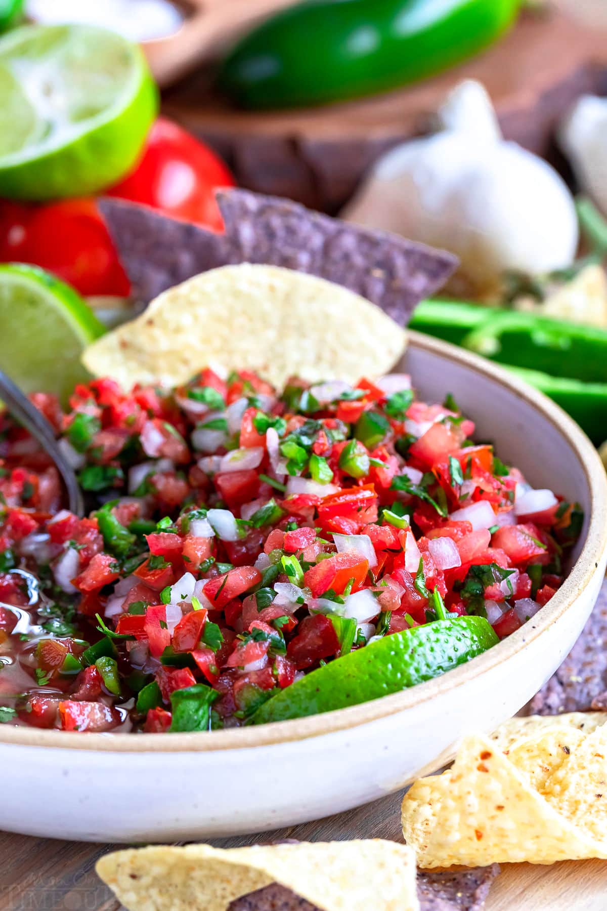 beautiful salsa in white bowl with lime wedges and tortilla chips. 