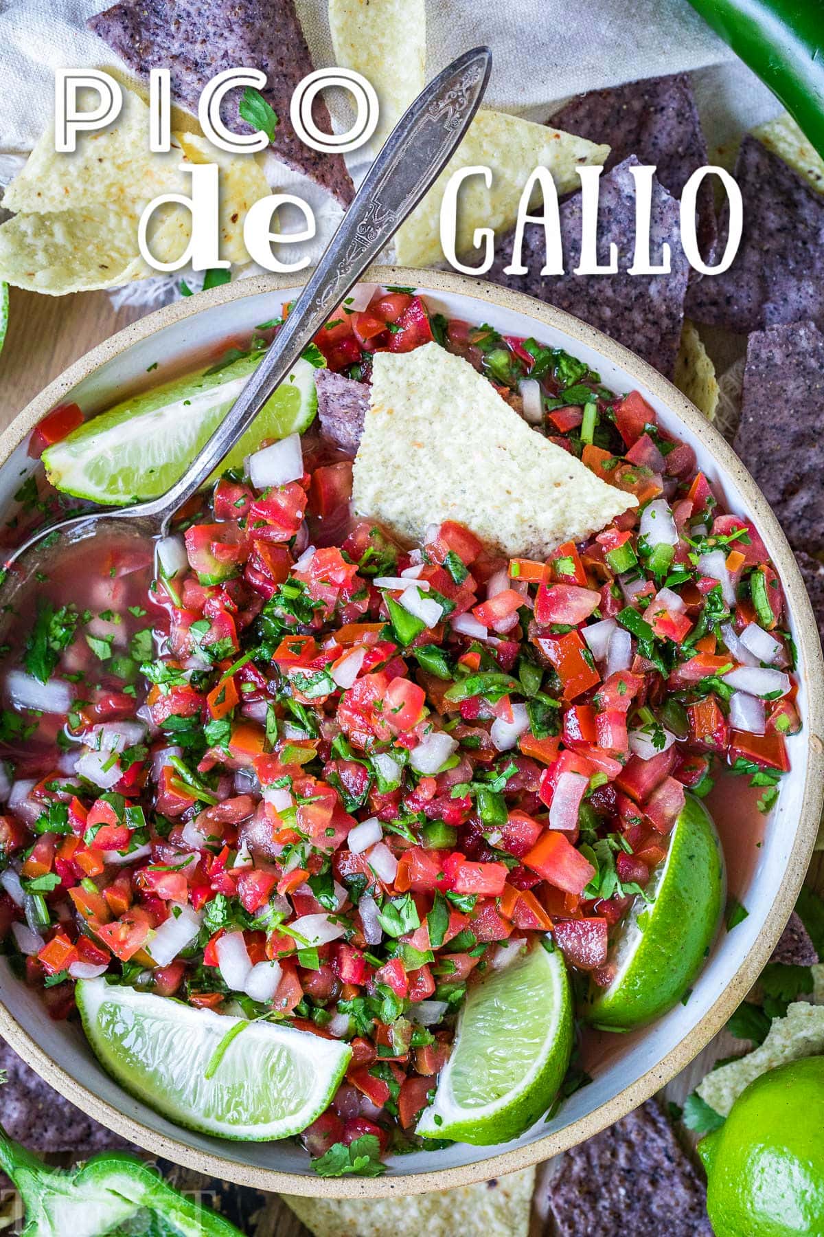 top down view of pico de gallo in clay bowl garnished with lime wedges and surrounded by chips. title overlay at top of image.