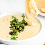 chip being dipped in queso blanco with charred poblanos on top.