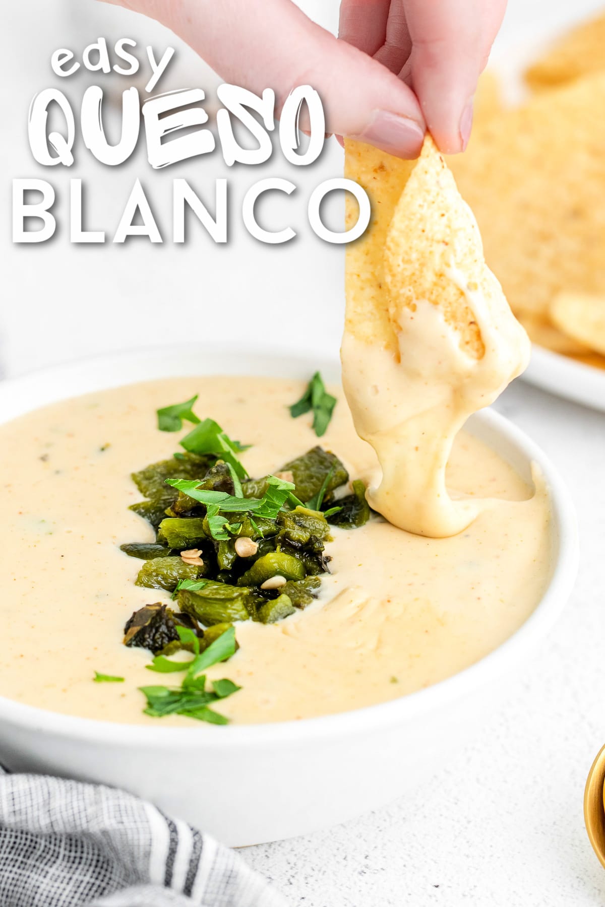 chip being dipped in queso blanco with charred poblanos on top. title overlay at top of image.