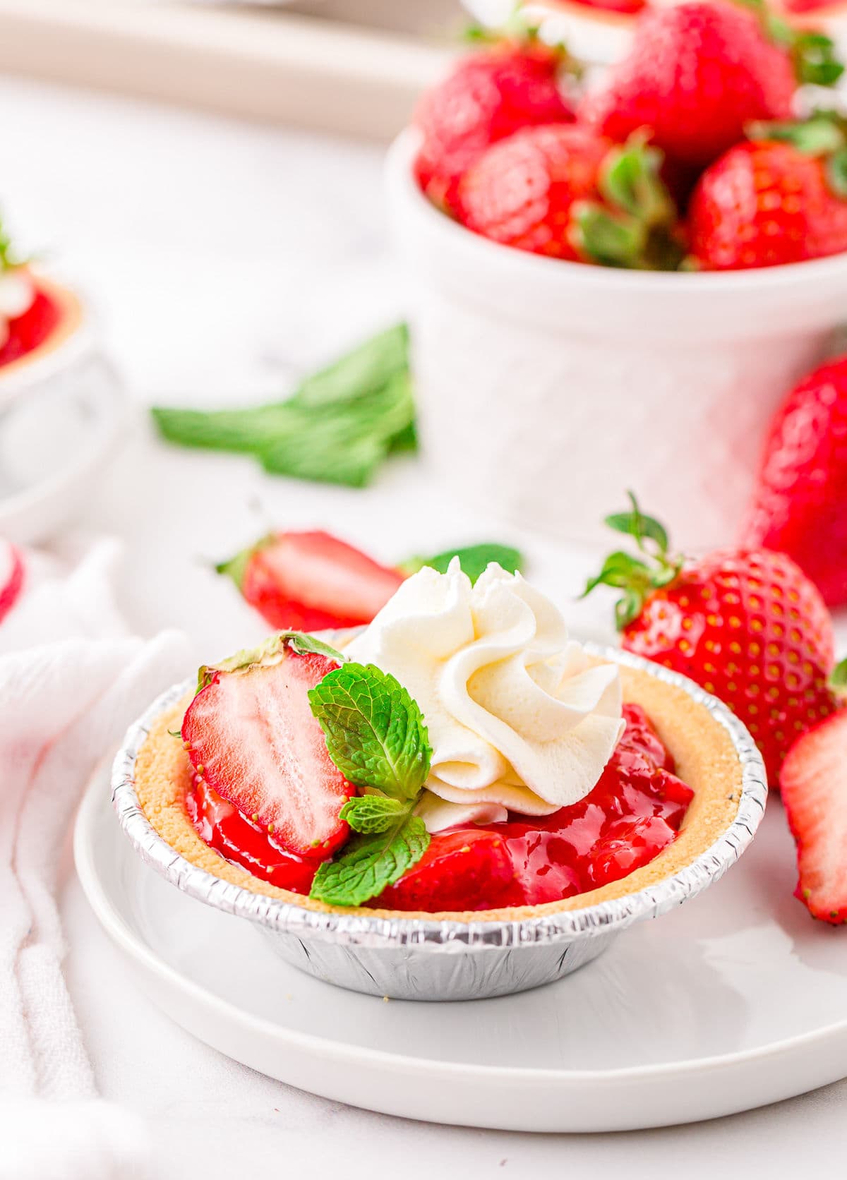 strawberry mini pie topped with whipped cream and fresh strawberries.