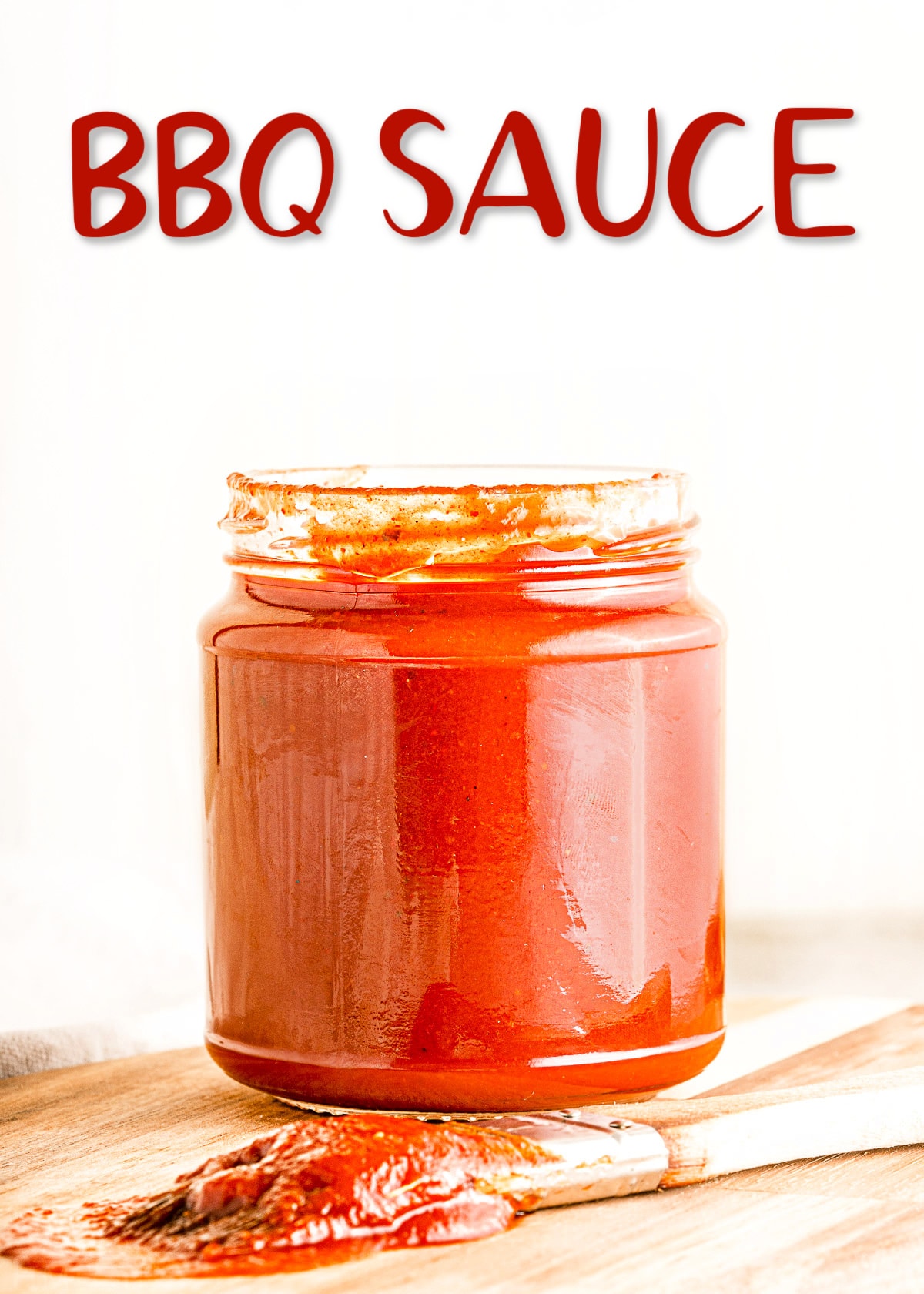 homemade bbq sauce is glass jar sitting on wood cutting board with title overlay at top of image.