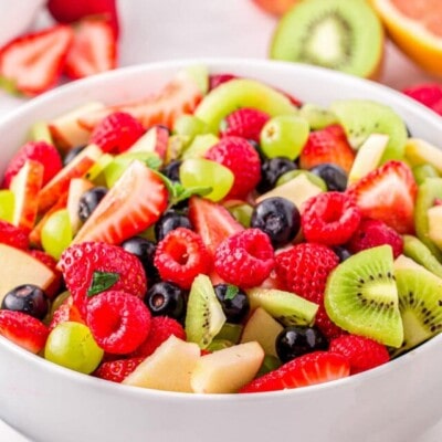 light and refreshing fruit salad with summer fruits in large white serving dish.