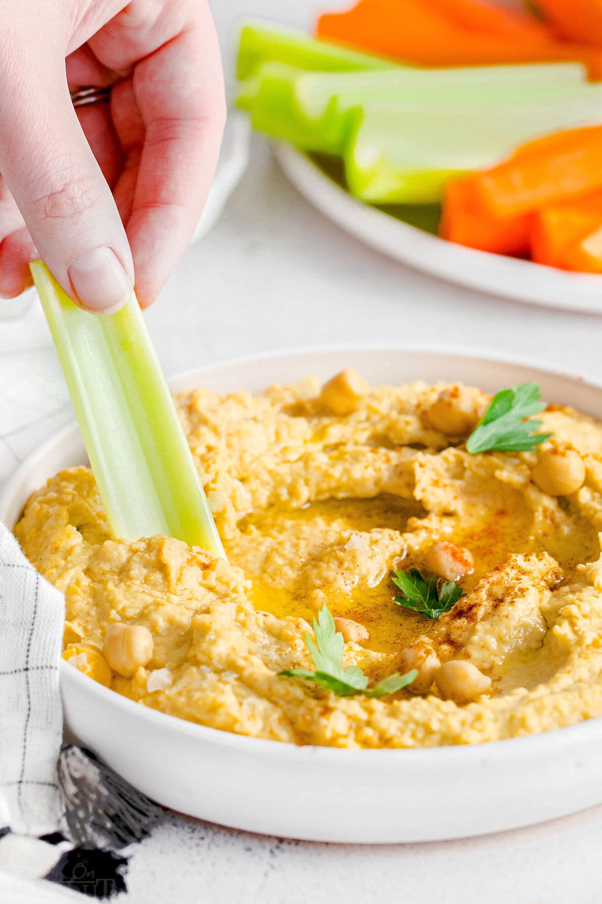 celery stick being dipped in hummus.