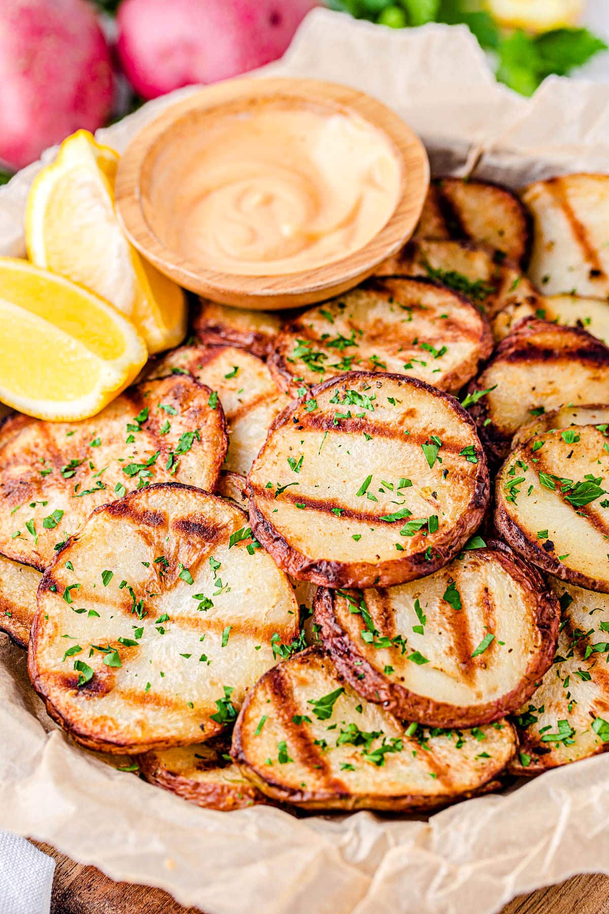 grilled potatoes served with spicy mayo dip and lemon wedges on wood tray.