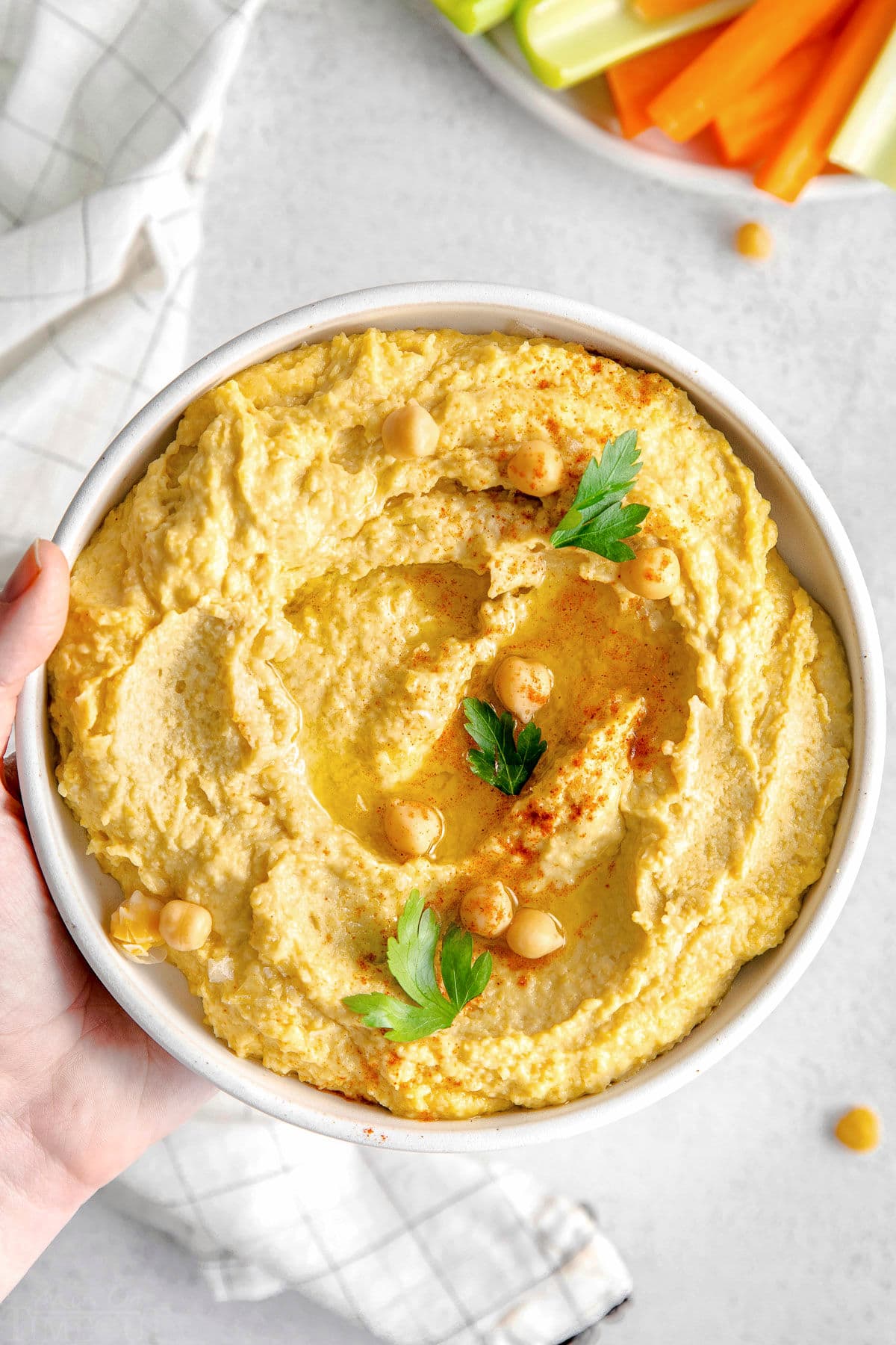 hand holding bowl of hummus.