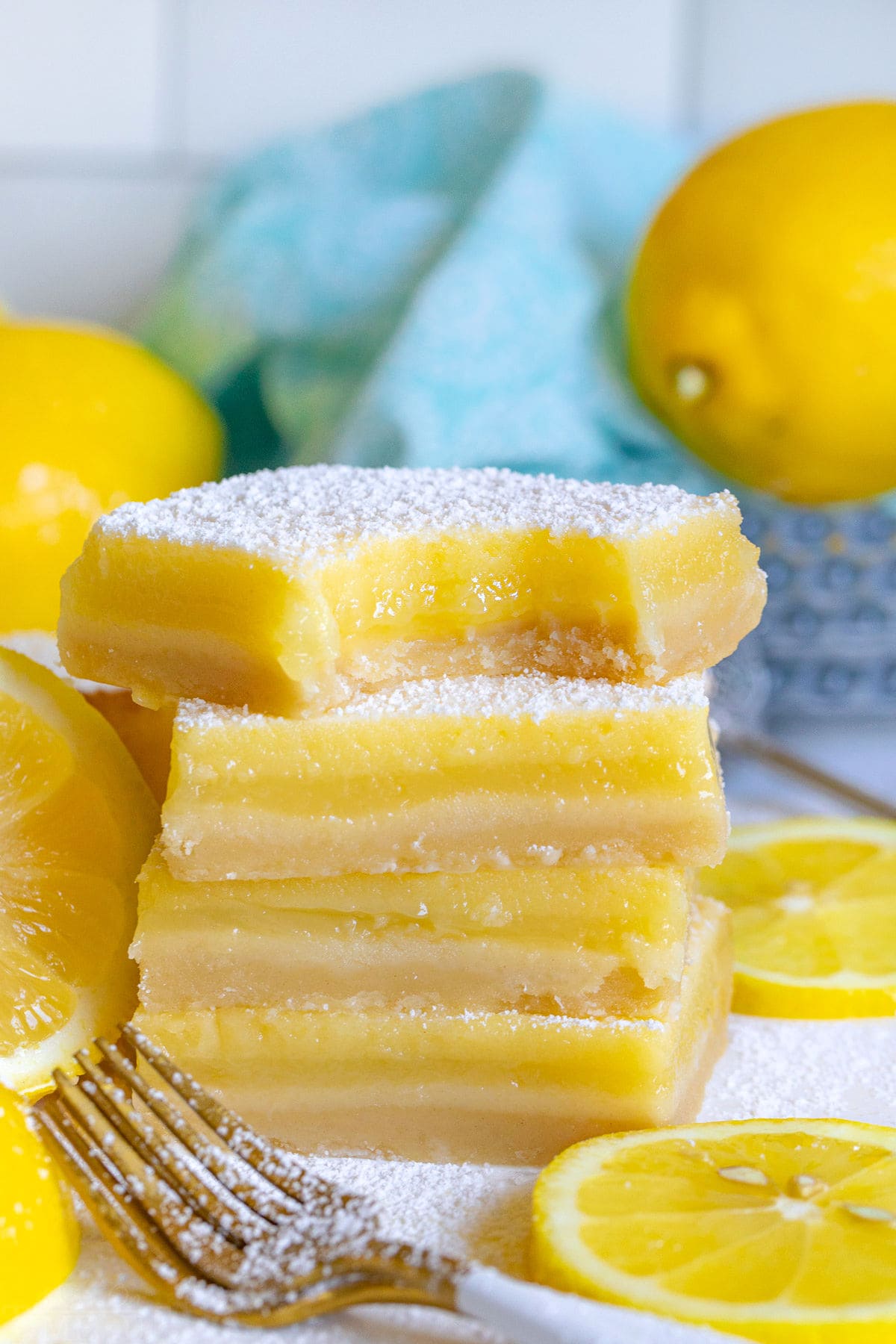 stack of four lemon bars with the top bar having a bite taken.