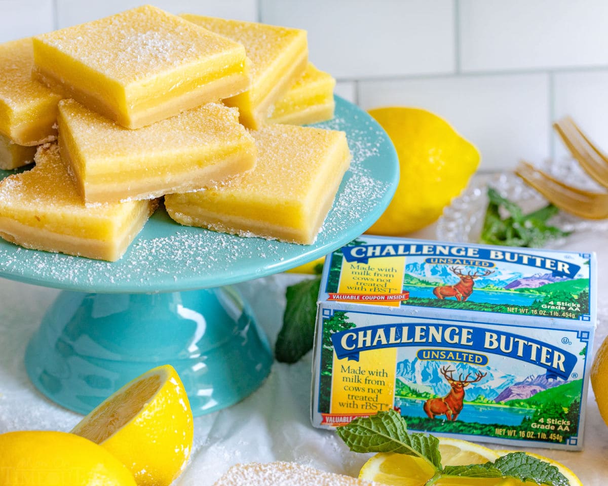 cake stand with lots of lemon bars next to box of butter.