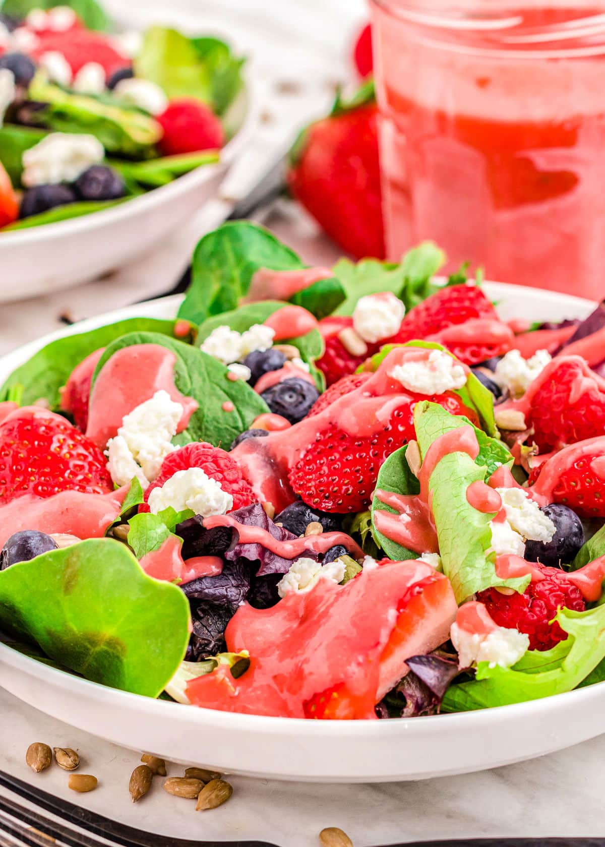 ready to enjoy summer berry salad with raspberry vinaigrette in jar in background.