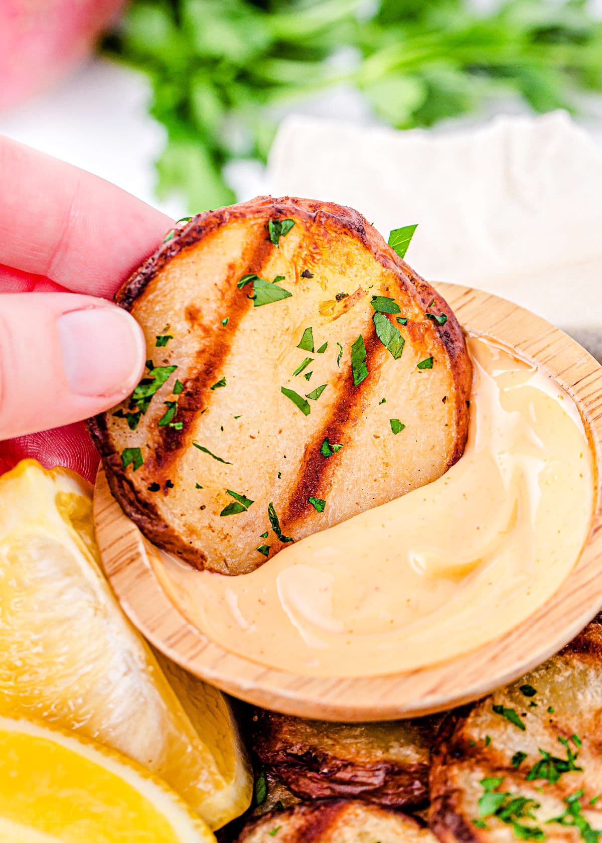 grilled potato slice being dipped in spicy mayo dip.