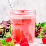 raspberry vinaigrette in glass jar in front of salad greens.