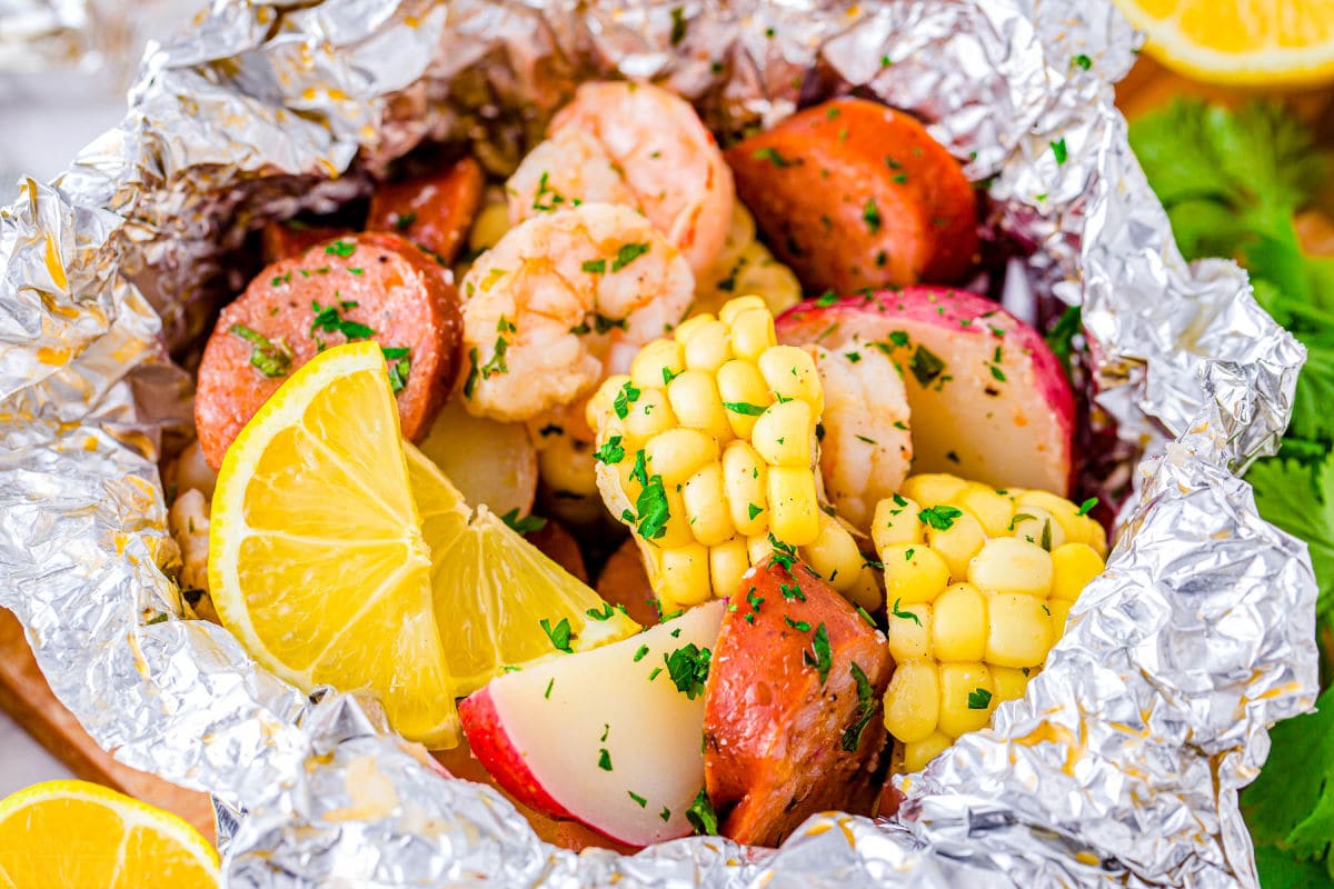 close up look at shrimp foil packets with corn, potatoes, shrimp, sausage and herbs. 