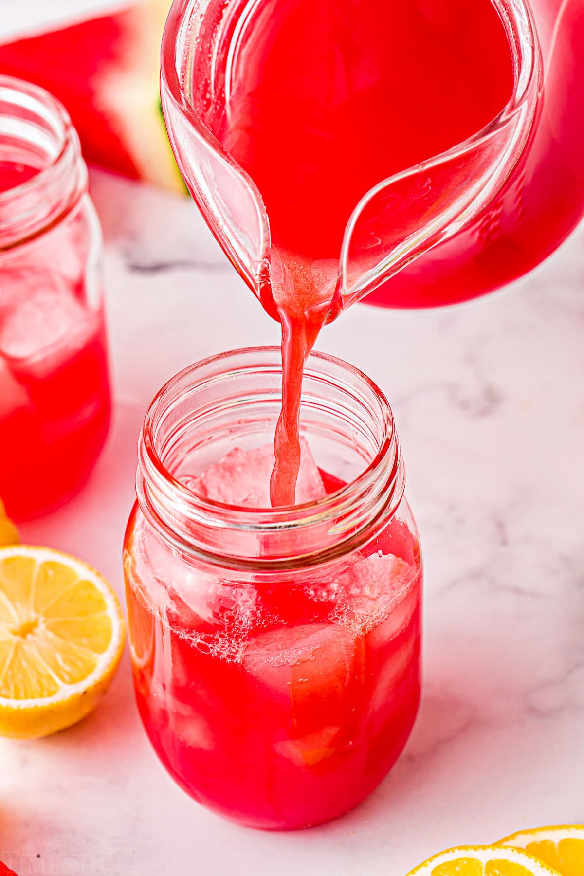 watermelon lemonade being poured into large glass.