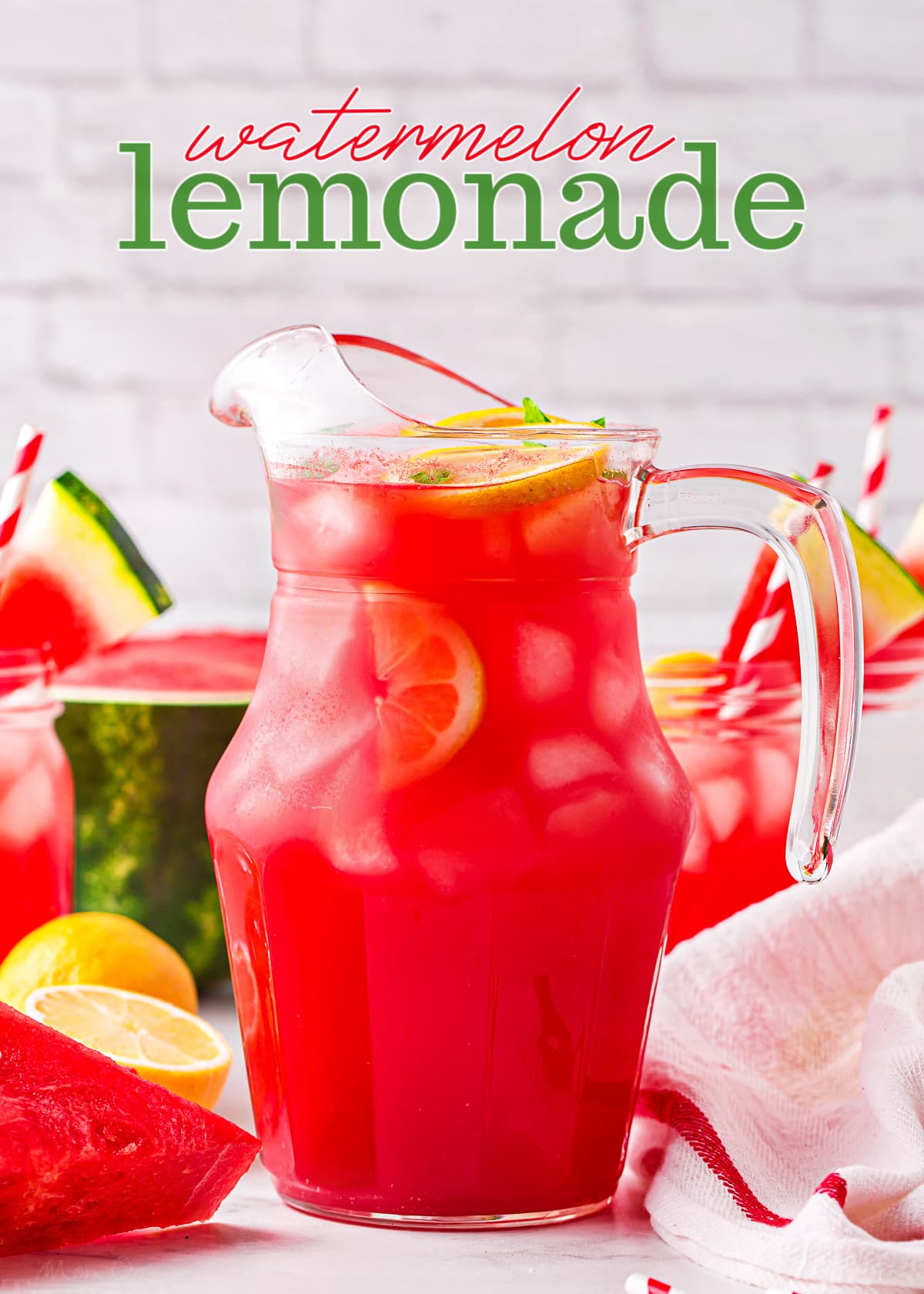 watermelon lemonade in a tall glass pitcher with watermelon slices and lemons scattered about. title overlay at top of image.