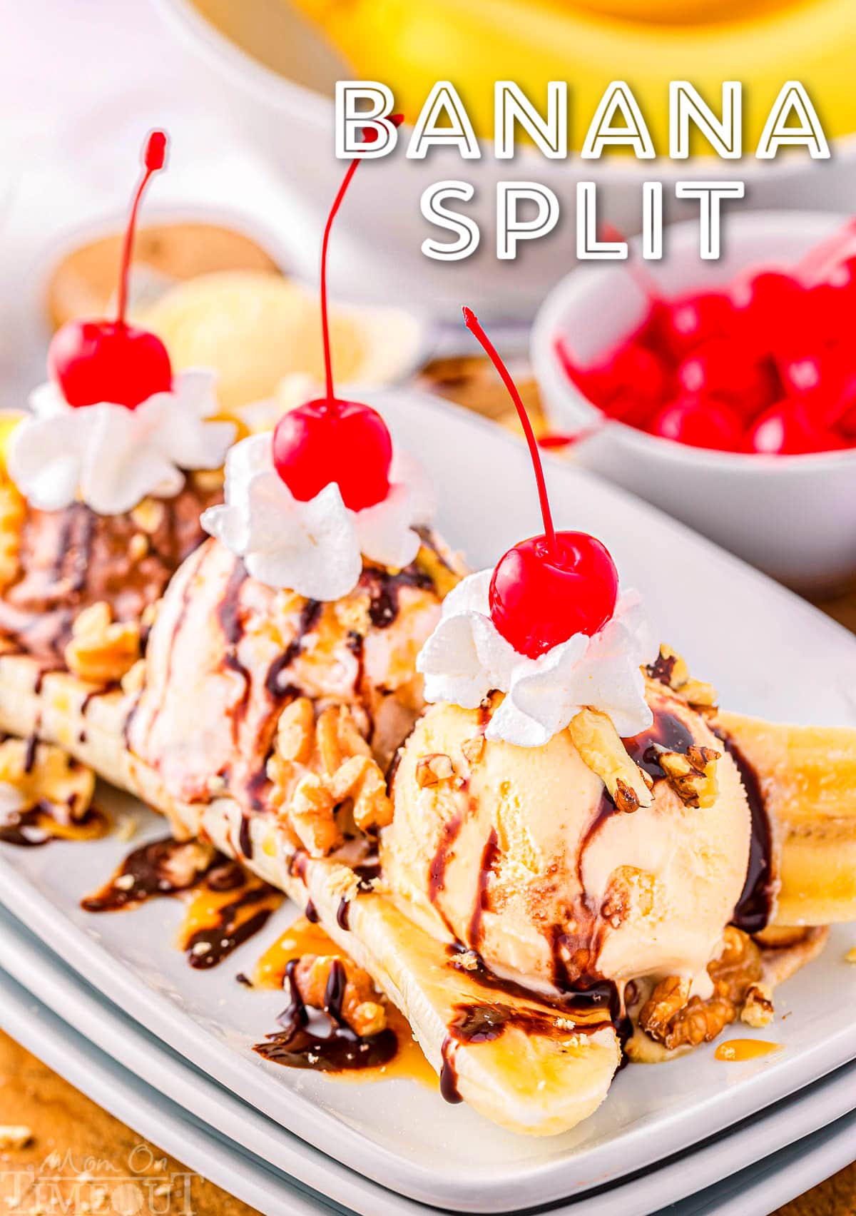 banana split on white plate topped with whipped cream and maraschino cherries. title overlay at top of image.