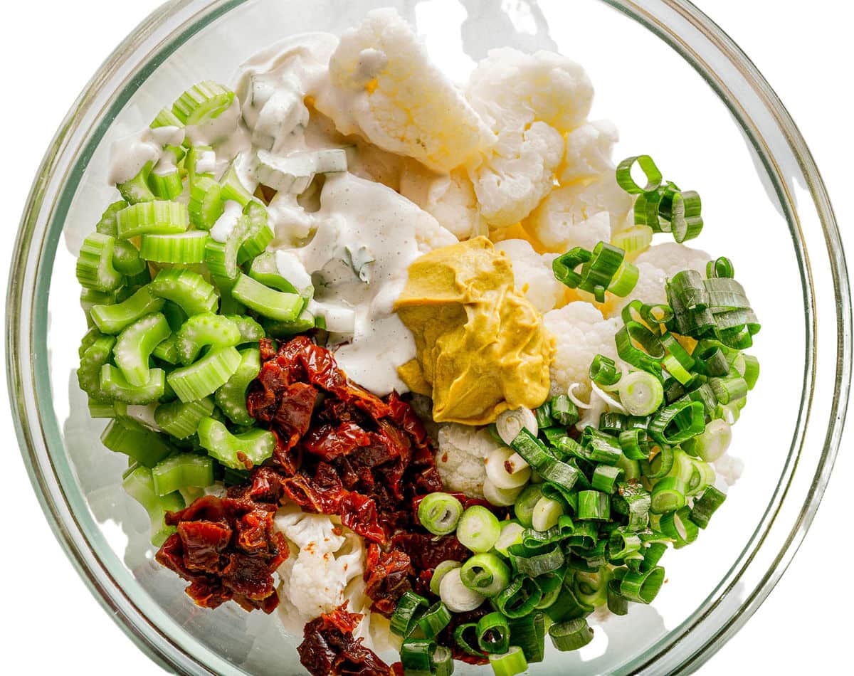 all salad ingredients in large glass bowl ready to be mixed together.