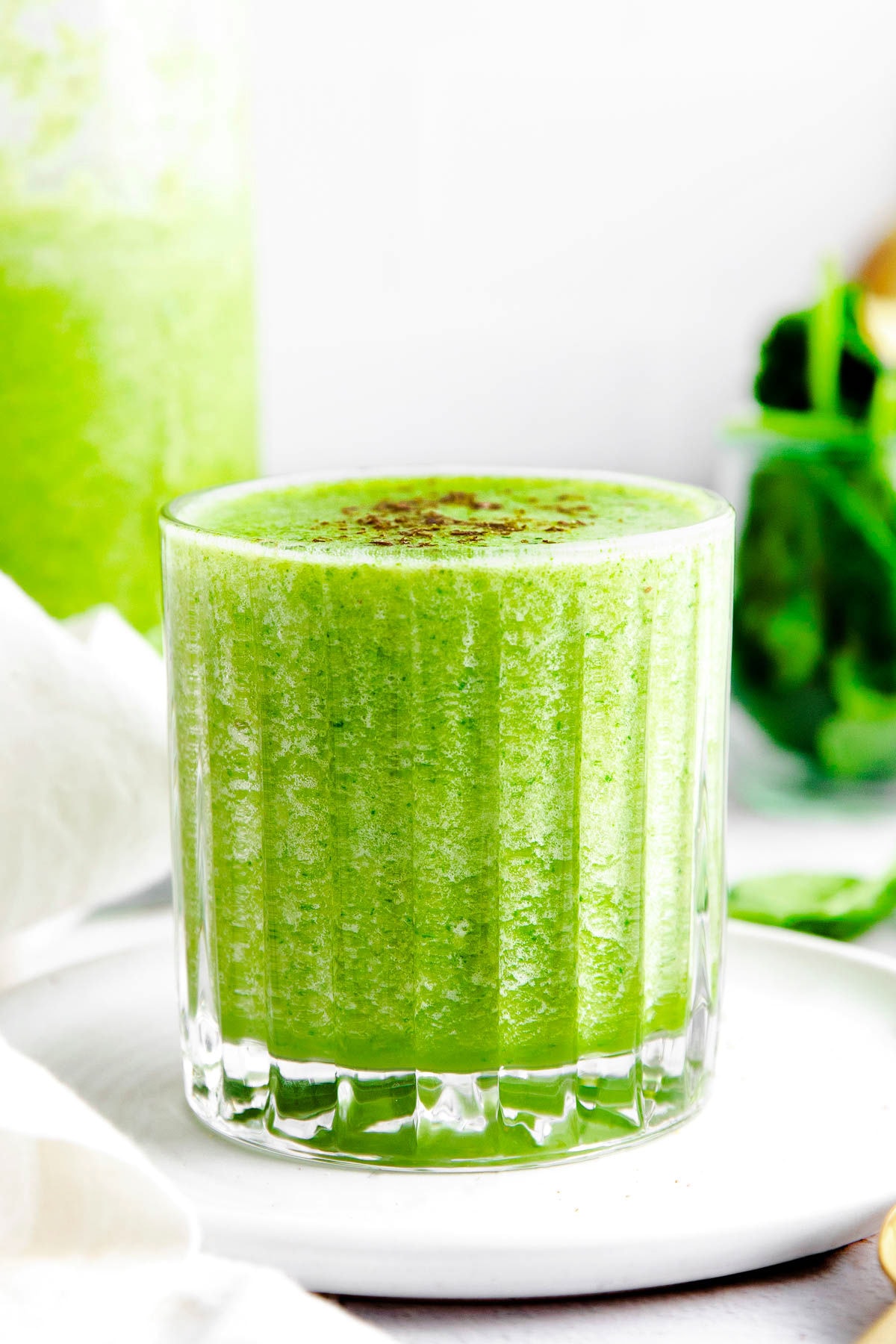 front view of small glass filled to the brim with a green smoothie.