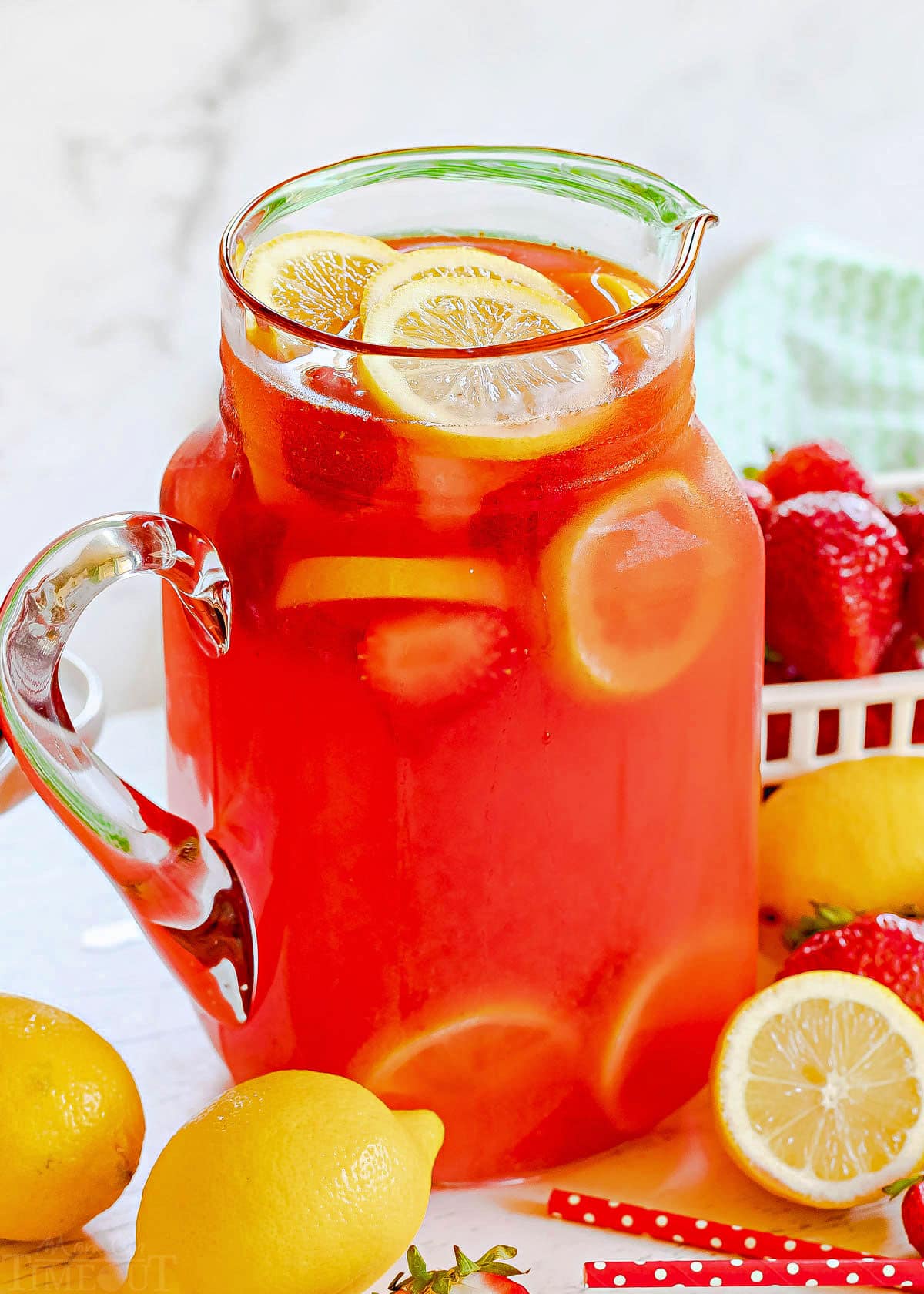 pitcher full of strawberry lemonade with fresh lemon slices and strawberries.