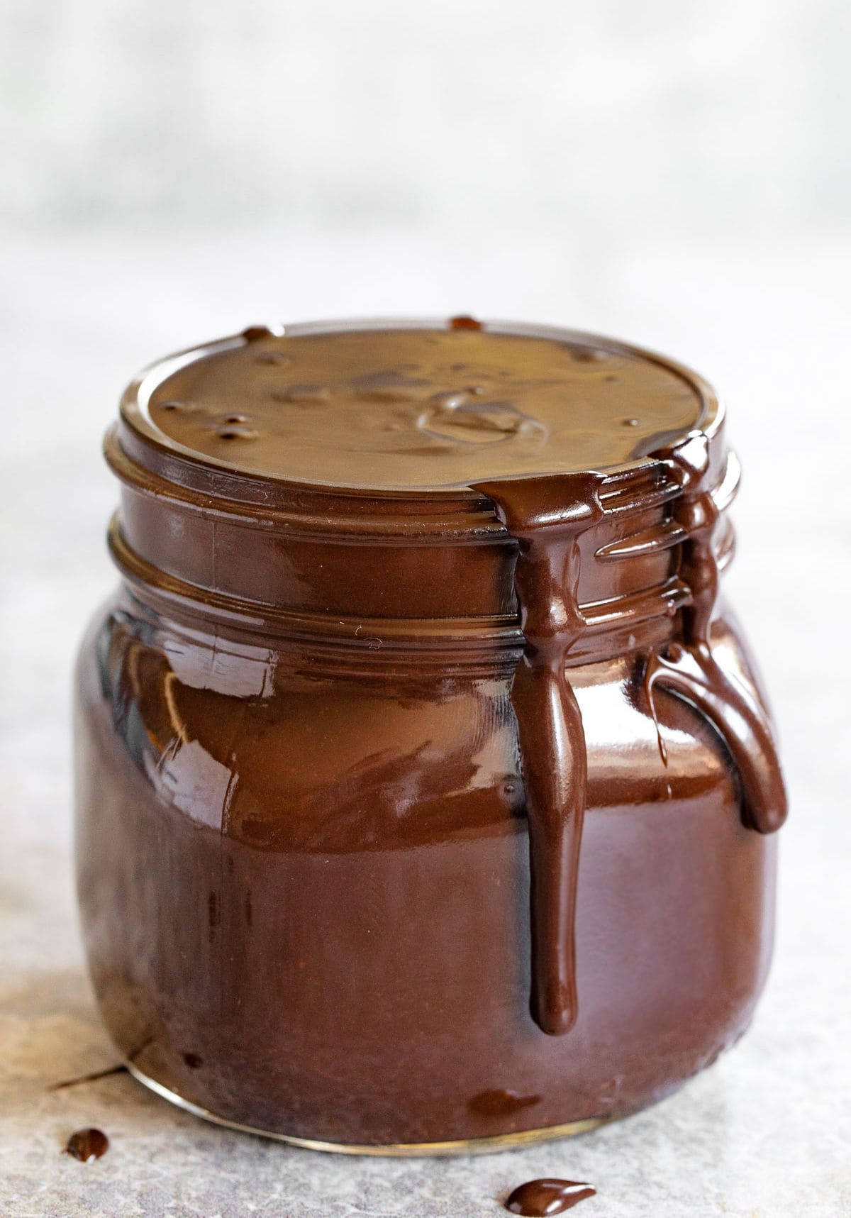 jar of hot fudge sauce with some dripping over the top of the jar.
