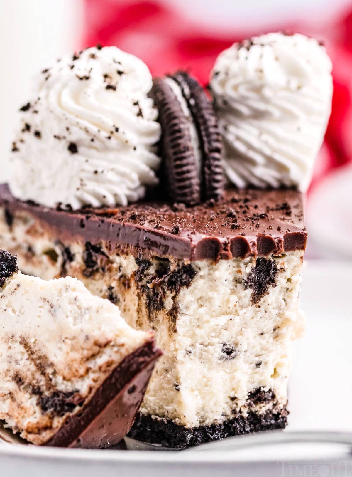 nice close up look at creamy texture of cheesecake and the layer of ganache on top. cheesecake slice has a bite removed.