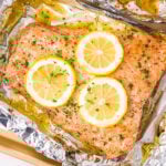 baked salmon in foil topped with lemon slices and fresh parsley.