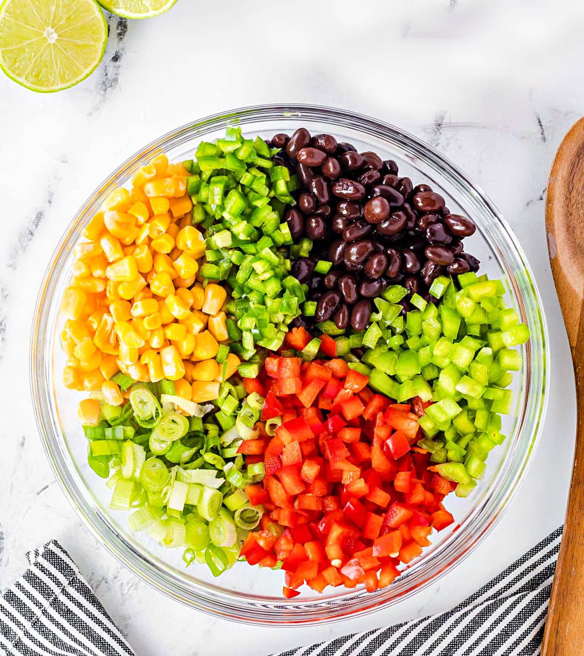 black bean corn salsa ingredients prepped and in a clear glass bowl ready to be mixed together.