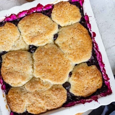 top down look at baked blueberry cobbler in white baking dish.