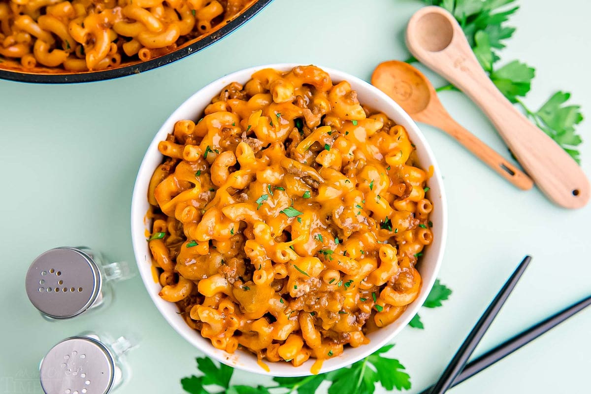 homemade hamburger helper served in a small white bowl on a mint green background.