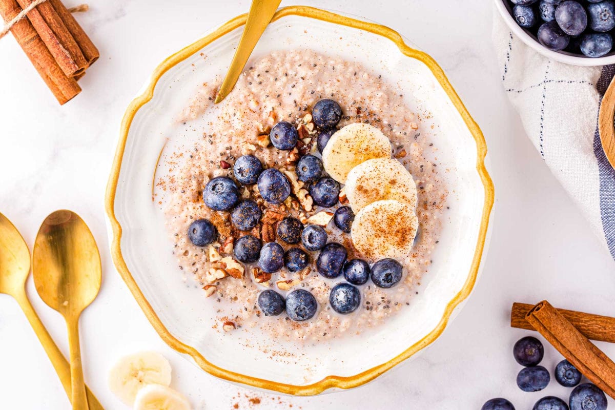 top down look at bowl of oatmeal topped with fresh fruit, pecans and cinnamon.