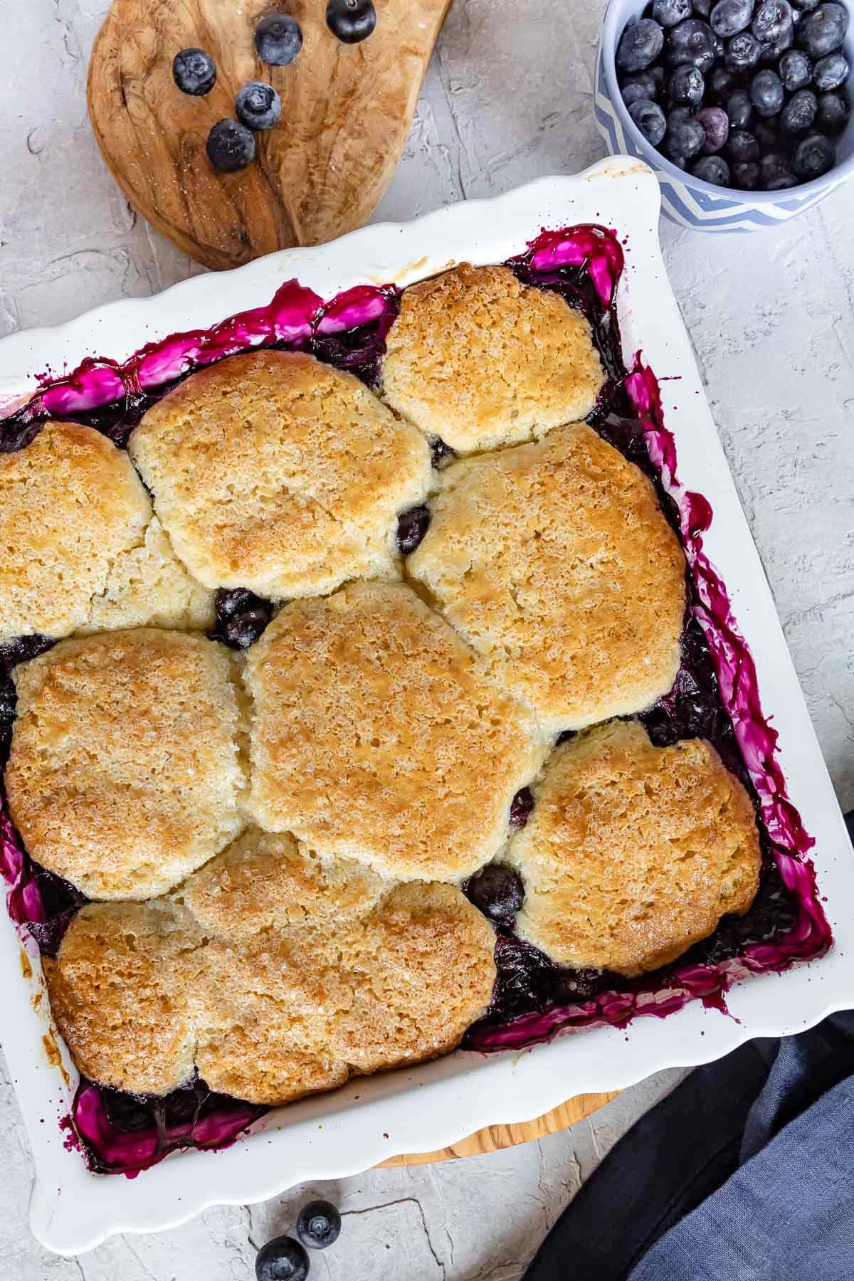 top down look at baked blueberry cobbler in white baking dish.