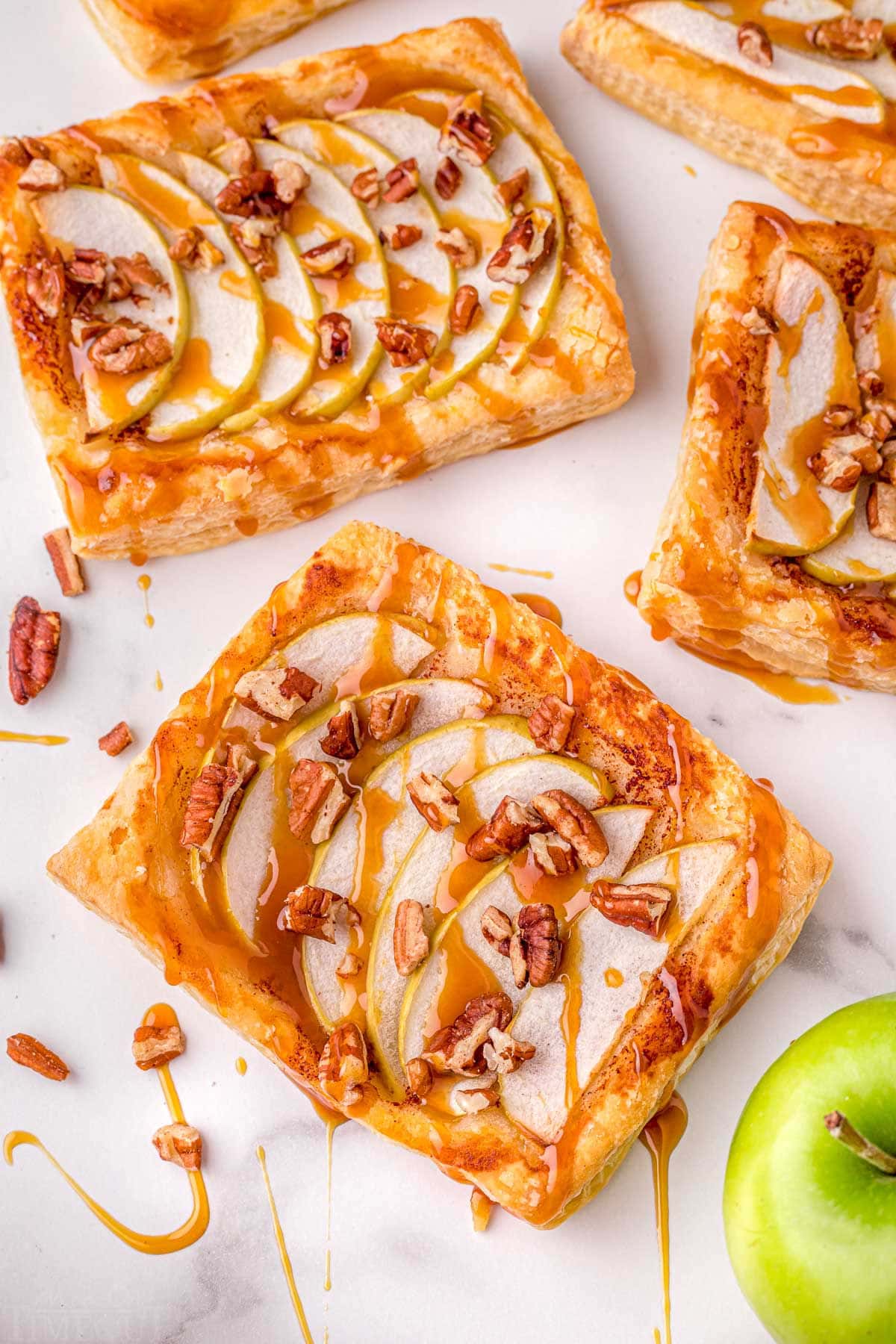 puff pastry apple tart recipe sitting on marble surface with drizzle of caramel sauce.