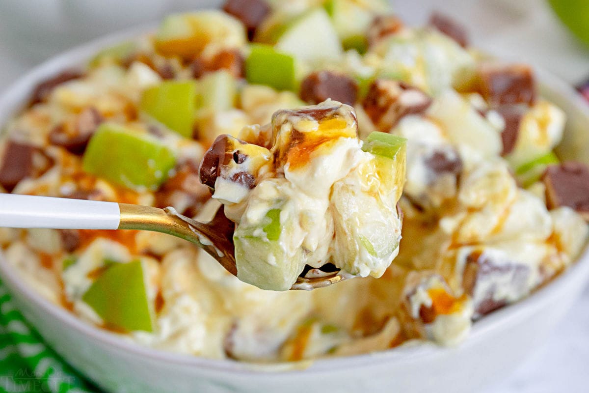 spoonful of caramel apple salad held in front of serving bowl.