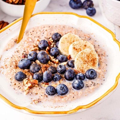 close up look at steel cut oats in bowl topped with blueberries, banana slices and pecans.